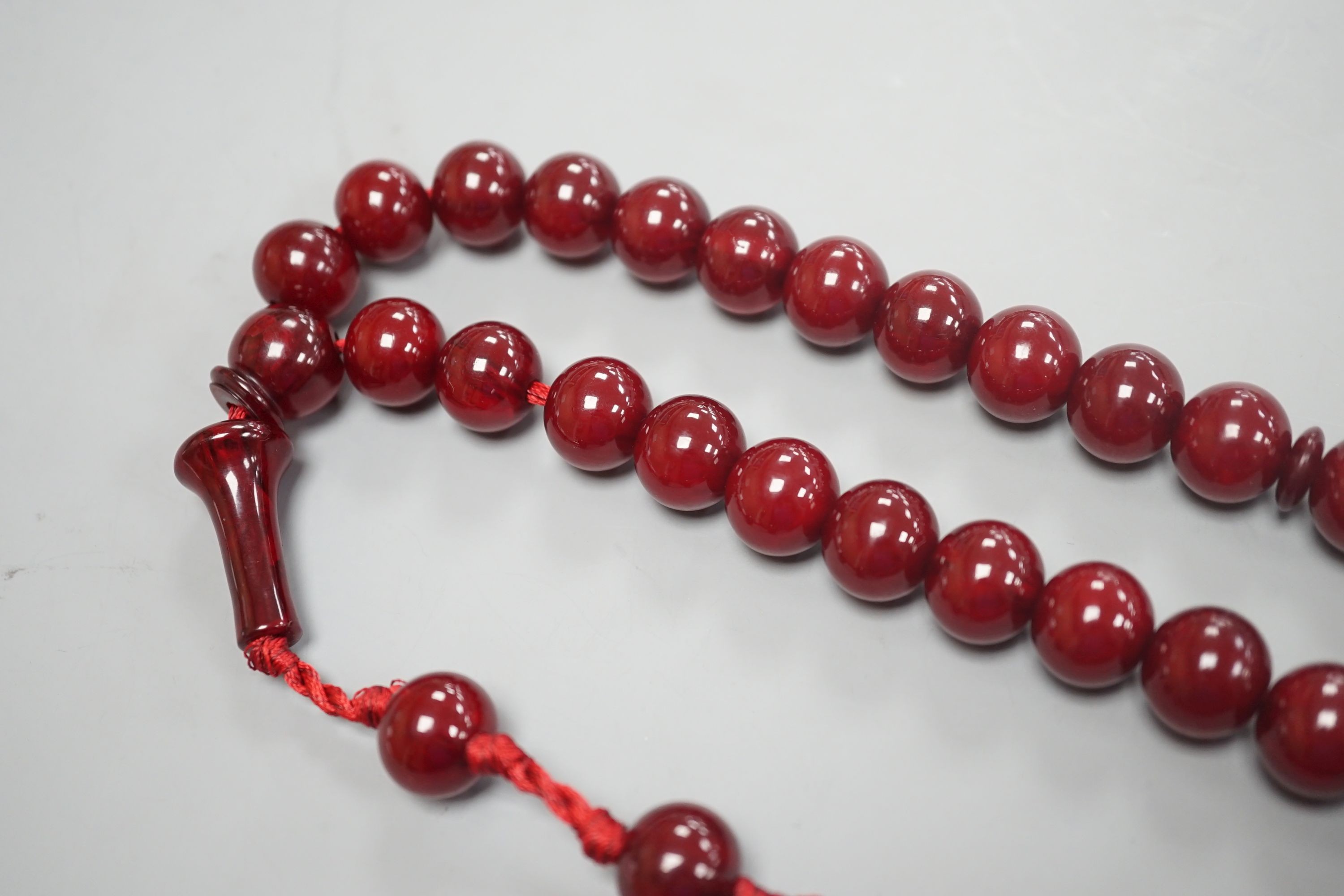 A single strand cherry amber bakelite necklace, 92cm including tassel, gross weight 88 grams.